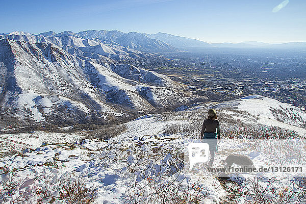 Hochwinkelaufnahme einer Frau mit Hund auf einem Berg im Winter