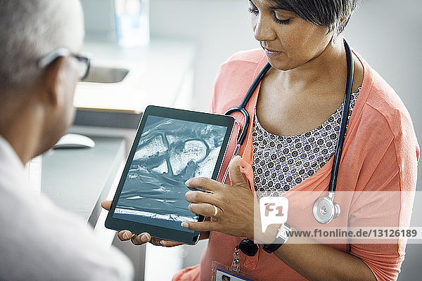 Ärztin erklärt Patientin das Röntgenbild am Tablet-Computer in der Klinik