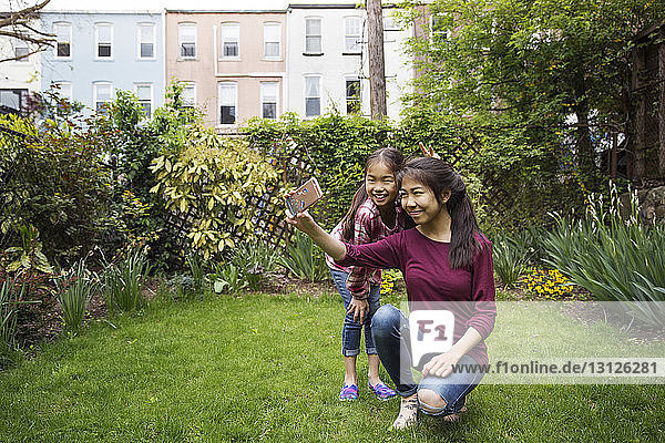 Lächelnde Schwestern  die sich in der Stadt gegen Pflanzen setzen