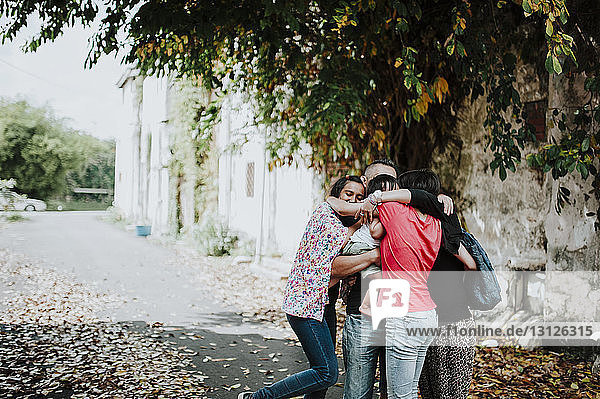 Glückliche Familie umarmt sich im Stehen auf der Straße