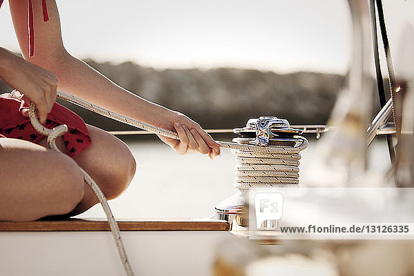 Ausgeschnittenes Bild einer Frau  die ein Seil auf einem Boot bindet
