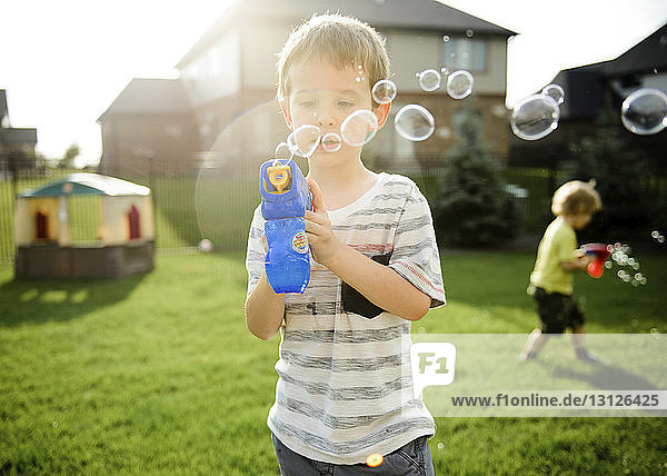 Brüder  die mit Blasenspielzeugpistolen spielen  während sie im Hof stehen