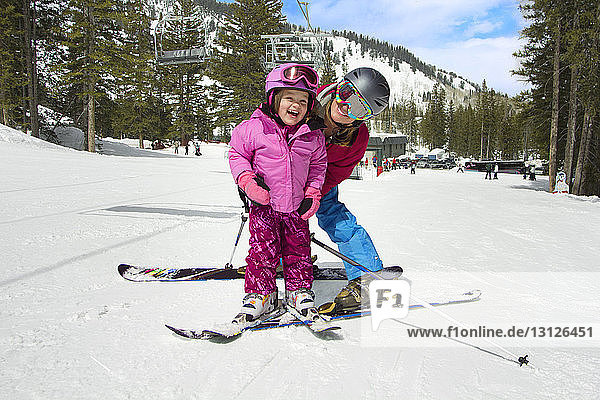Mother and daughter skiing on snow covered field