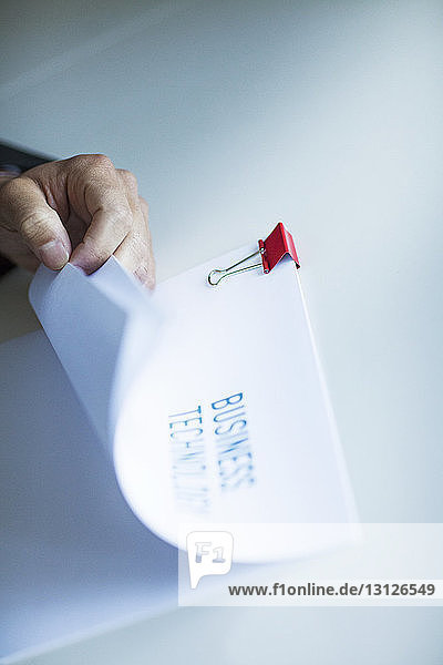 Cropped image of hand holding documents at table