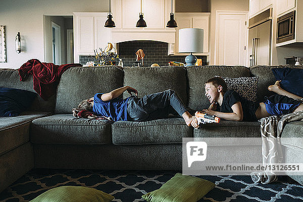 Glückliche Brüder liegen zu Hause auf dem Sofa