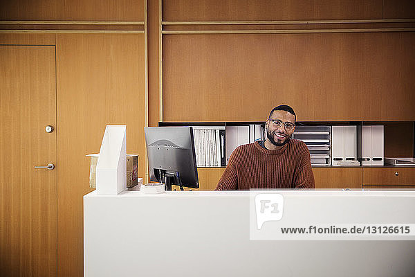 Porträt eines lächelnden Geschäftsmannes  der am Desktop-Computer im Büro sitzt