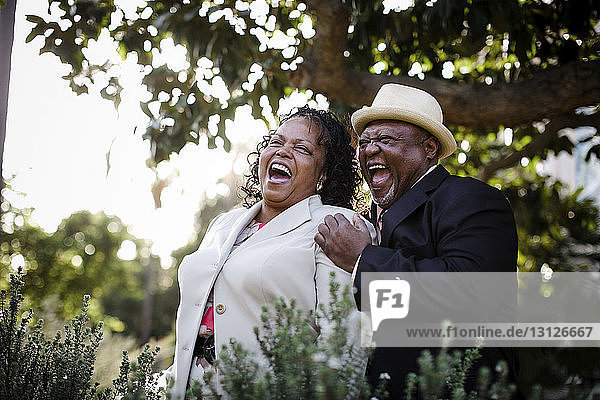 Happy senior couple laughing while standing at park