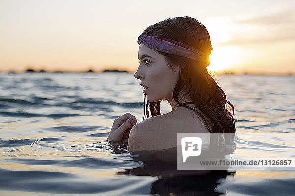 Nahaufnahme einer Frau im Wasser am Strand bei Sonnenuntergang