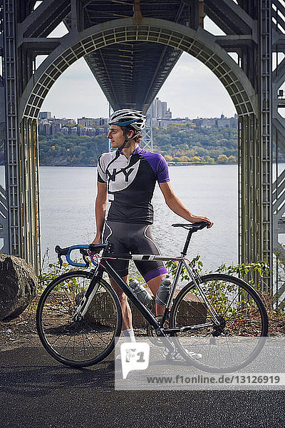 Man standing with bicycle by George Washington Bridge