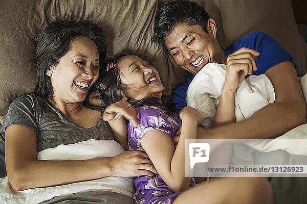 Overhead view of happy family in bed at home