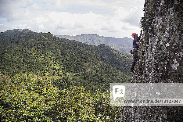 Seitenansicht eines Wanderers beim Felsklettern gegen Berge