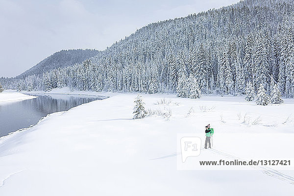 Hochwinkelaufnahme einer Wanderin  die auf einem schneebedeckten Feld stehend fotografiert