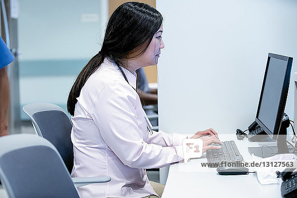 Seitenansicht einer Ärztin  die einen Desktop-Computer im Krankenhaus benutzt