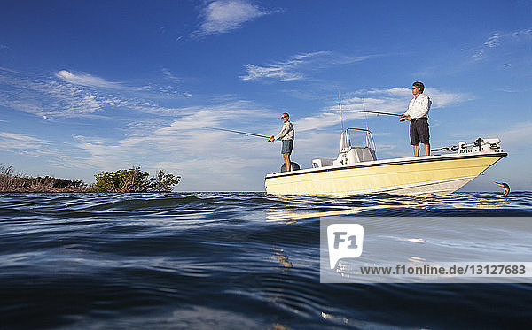 Niedrigwinkelansicht von Männern  die auf einem Boot stehen und gegen den Himmel fischen