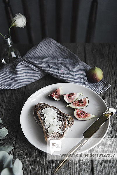 Hochwinkelansicht von Brot und Sahne mit Feige im Teller auf dem Tisch
