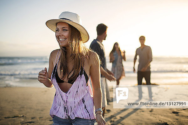 Glückliche Frau steht am Strand mit Freunden im Hintergrund