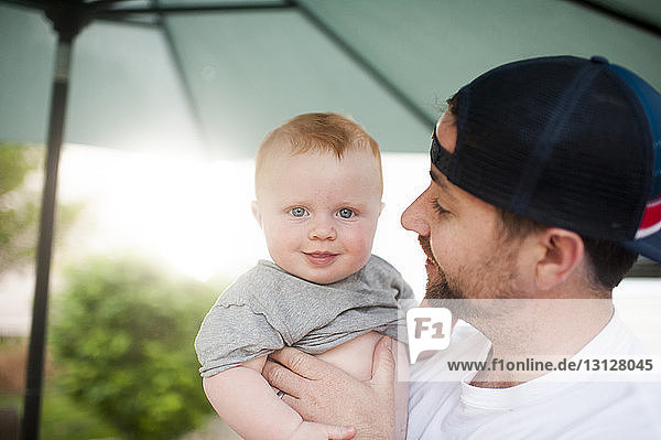 Portrait of cute son carried by father at backyard