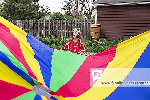 Mädchen steht an farbenfrohem Fallschirm im Park