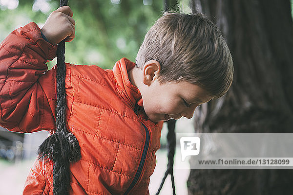 Sorgloser Junge spielt auf Seilschaukel im Park