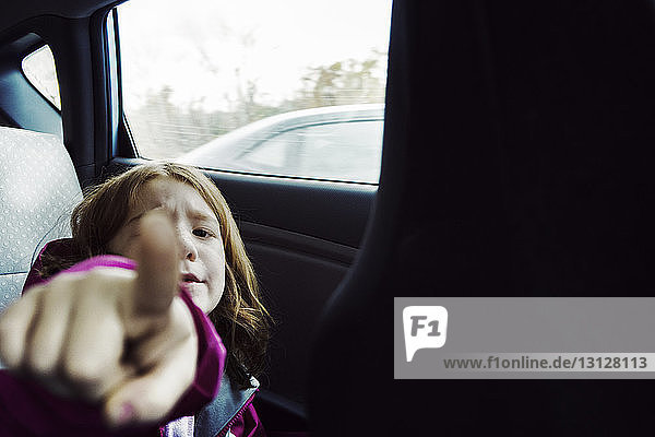 Porträt eines Mädchens  das am Fenster sitzend im Auto zeigt