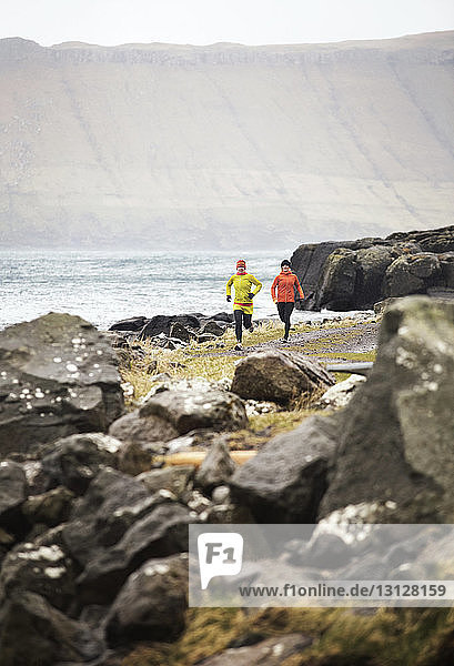 Freunde joggen auf einem Fußweg an der Küste