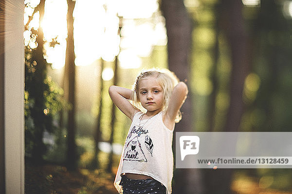Portrait of girl relaxing against trees at yard
