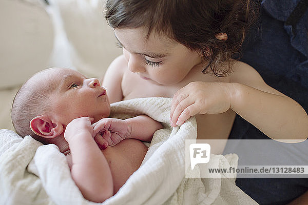 Sister looking at newborn brother by father at home
