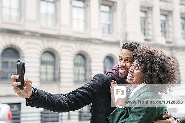Business couple taking selfie while standing in city