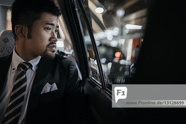 Thoughtful businessman looking through window in taxi
