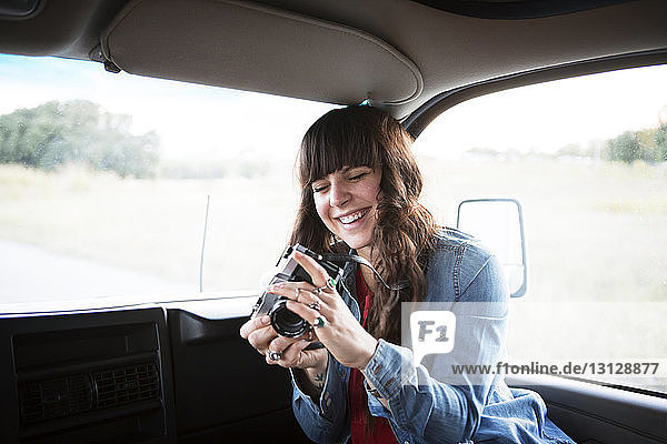Fröhliche Frau benutzt Kamera während der Fahrt im Wohnmobil