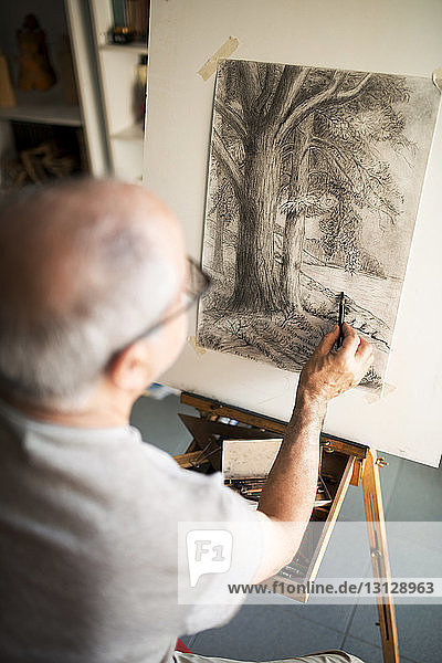 Älterer Mann skizziert zu Hause auf Leinwand
