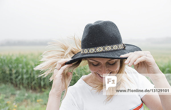 Close-up of happy woman wearing hat while standing against plants against sky