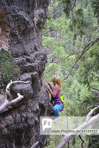 Hochwinkelaufnahme einer Frau beim Felsklettern im Wald