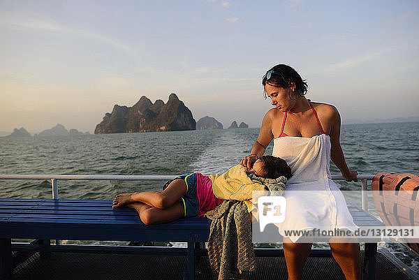 Mutter schaut auf Tochter  die auf dem Schoß schläft  während sie im Boot reist