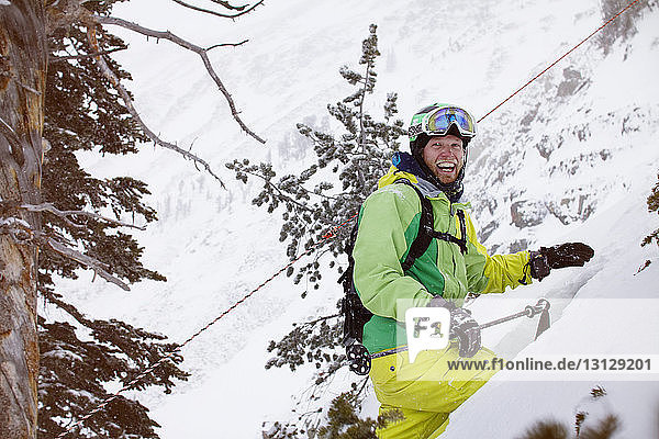 Fröhlicher Skifahrer wandert auf schneebedecktem Berg