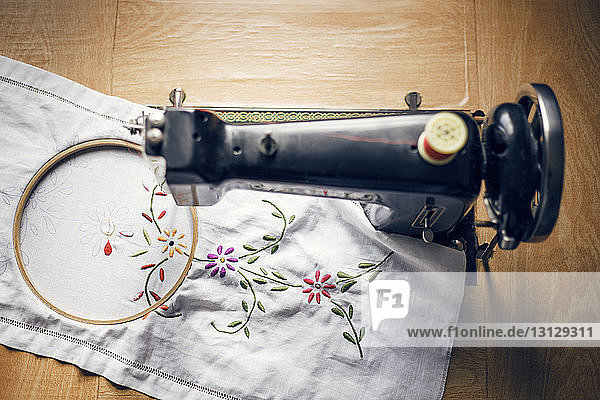Overhead view of fabric and embroidery machine on wooden table