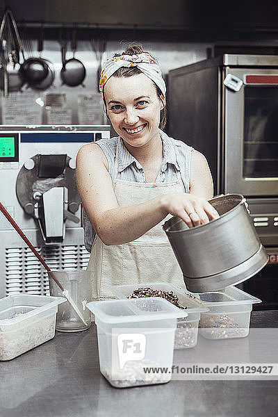 Porträt einer fröhlichen Frau  die in einer Großküche Eiscreme herstellt