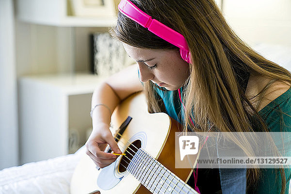 Teenager-Mädchen spielt Gitarre im Schlafzimmer