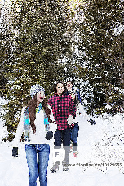 Happy family walking on snowy field in forest