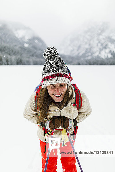 Smiling woman hiking on snow covered field