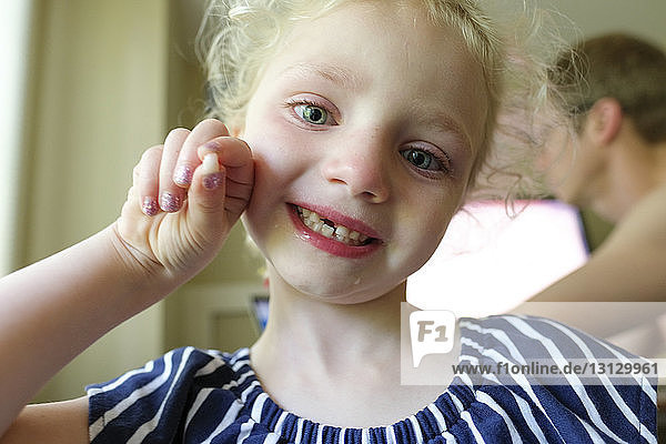 Nahaufnahme eines lächelnden Mädchens mit verlorenen Milchzähnen im Kampf gegen den Vater zu Hause