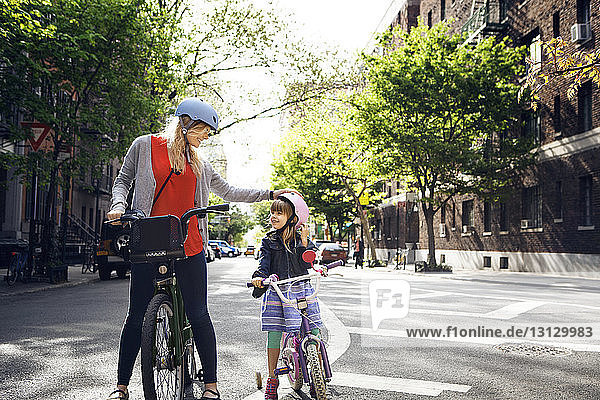 Mother and daughter with bicycles on city street