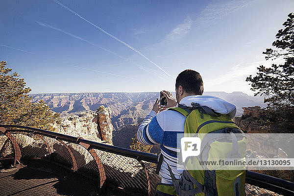 Hiker photographing mountains while standing at observation point