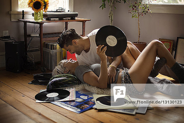Romantischer Mann liegt mit einer Frau zusammen  die zu Hause eine Schallplatte auf dem Boden hält