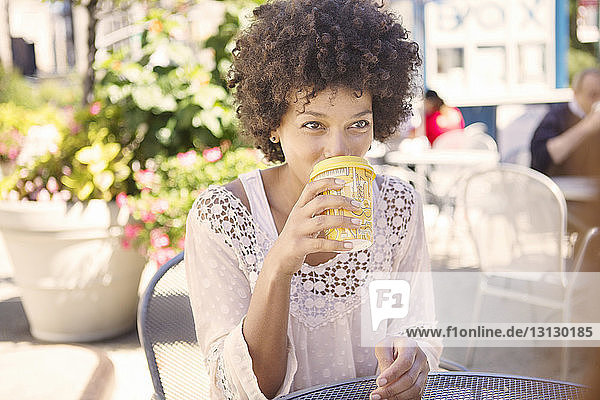 Woman drinking coffee while sitting in sidewalk cafe