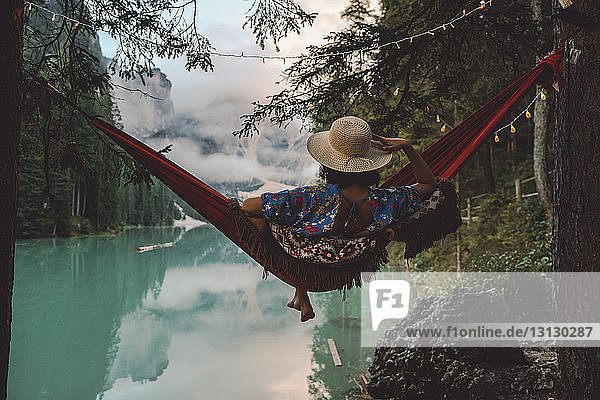 Young woman looking at view while sitting in hammock over lake
