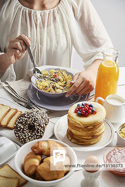 Midsection of woman having breakfast on table at home