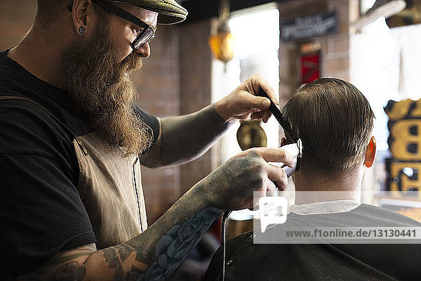 Friseur schneidet Männerhaare mit Elektrorasierer im Geschäft