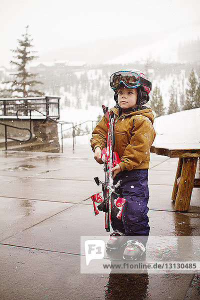 Junge hält Skibrett während Schneefall in Touristenort