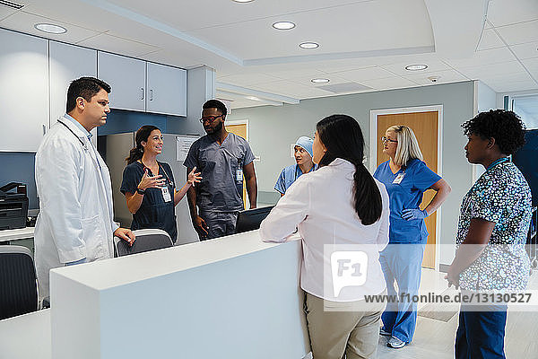 Kollegen sehen Ärztin an  die während des Treffens am Krankenhausempfang erklärt